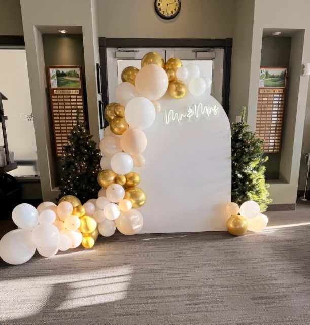 White and gold balloon garland around a white Mr and Mrs wedding backdrop